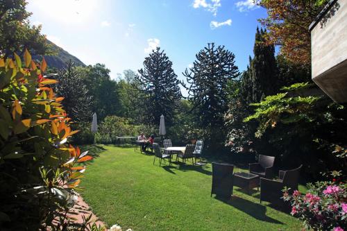 a garden with chairs and a table and some trees at Hotel Al Fiume in Tegna