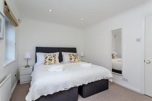 a white bedroom with a large bed with white sheets at Modern Mews House with Free Parking Space, and Patio by Huluki Sussex Stays in Brighton & Hove