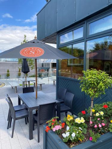 a table with an umbrella in front of a building at Sligo Park Hotel & Leisure Club in Sligo