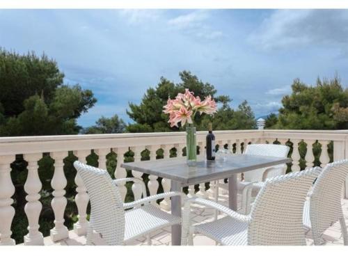 a table with chairs and a vase of flowers on a balcony at Apartments Villa Dingač in Gornji Dingač