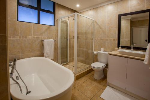 a bathroom with a tub and a shower and a toilet at Stay at The Point - Peaceful Plentiful Penthouse in Durban