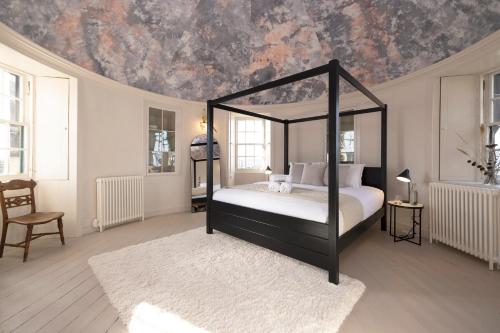 a bedroom with a black canopy bed with a ceiling at JOIVY Observatory House & Apartment in Edinburgh