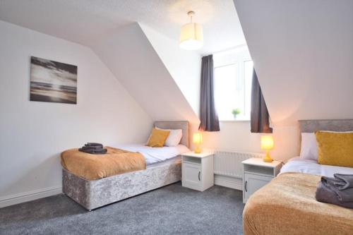 a attic bedroom with two beds and two lamps at St Katherines House - by TJ Serviced Property in Peterborough