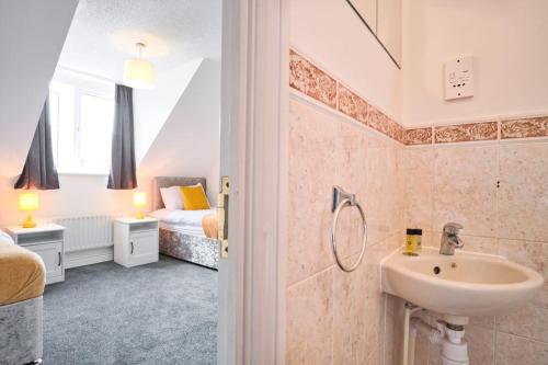 a bathroom with a sink and a bedroom with a bed at St Katherines House - by TJ Serviced Property in Peterborough