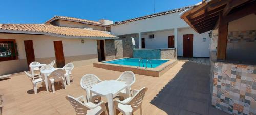 une terrasse avec des chaises blanches et une piscine dans l'établissement Hotel Terra Mater, à Porto Seguro