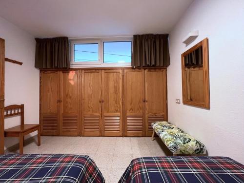 a bedroom with wooden cabinets and a bed and a window at Tamarán 311 in Playa del Ingles