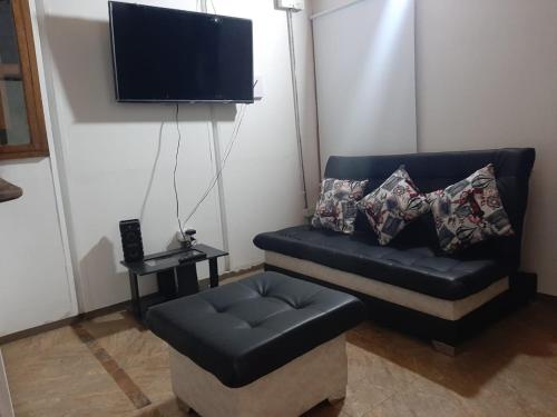 a black leather couch with a ottoman and a television at Casa de Campo Condina, hospedaje Familiar en la Naturaleza in Pereira