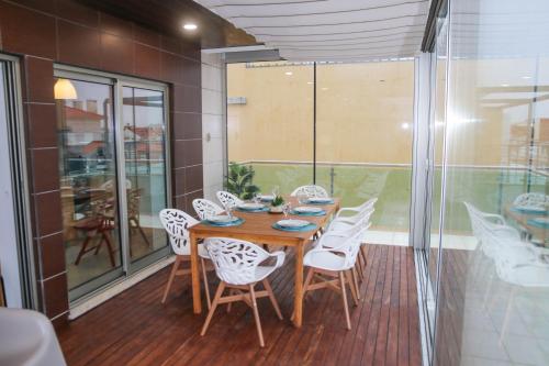 a dining room with a wooden table and white chairs at Casas e Quintas de Praia in Praia da Barra