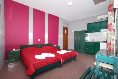 a bedroom with a red bed and a pink wall at Ilias Studios in Patitiri