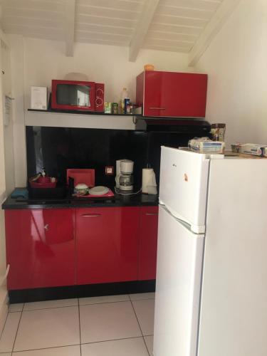 a kitchen with red cabinets and a white refrigerator at Kaban‘ Malaka in Petit-Bourg