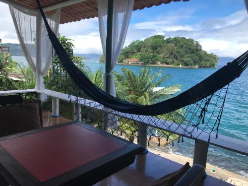 a hammock on the porch of a house overlooking the ocean at Cabana do Mar in Angra dos Reis