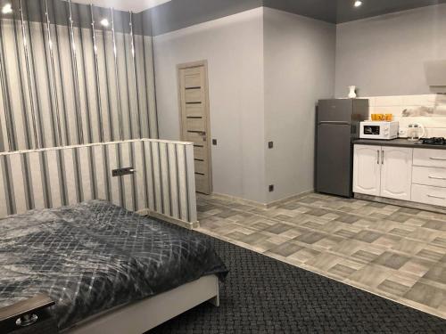 a bedroom with a bed and a kitchen with a refrigerator at Аpartments Central Town Містечко Центральне з власним паркінгом та документами на проживання in Ivano-Frankivsʼk