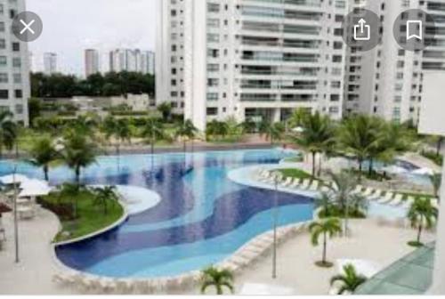 ein großer Pool mit Palmen und Gebäuden in der Unterkunft Apartamento Luxo Le Parc in Salvador
