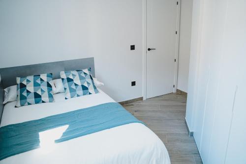 a bedroom with a white bed with blue accents at Apartamentos Turia Teruel in Teruel