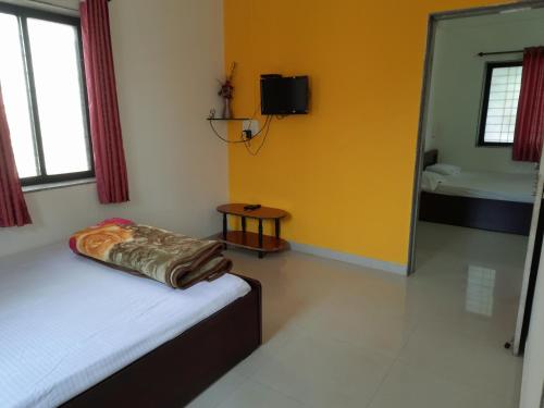 a bedroom with a bed and a tv and a mirror at Trimurti Holiday Home in Panchgani