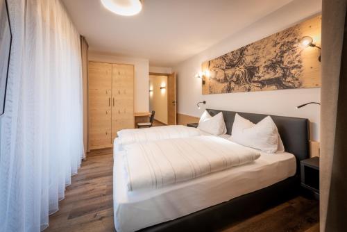 a bedroom with a large bed with white sheets at CHALET NORA in San Vigilio Di Marebbe