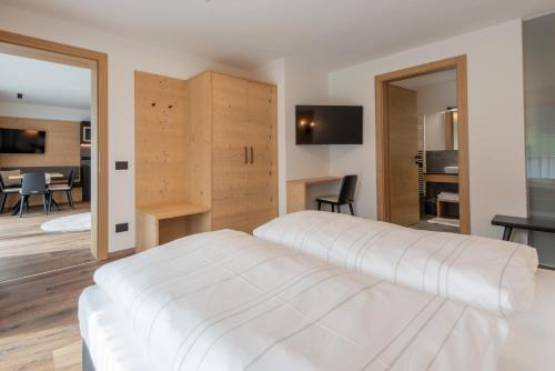 a bedroom with a white bed and a dining room at CHALET NORA in San Vigilio Di Marebbe