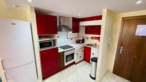 a kitchen with red cabinets and a white refrigerator at Senorio Entrada puntaprima in Torrevieja