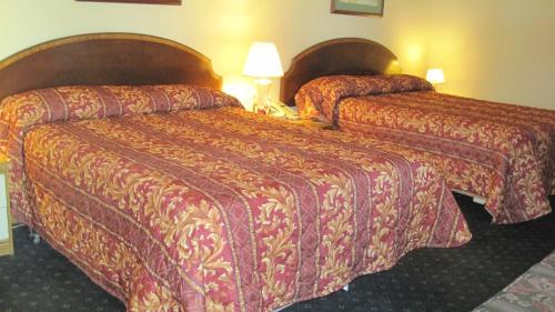 a hotel room with two beds and a lamp at Rosecourt Motel in Stratford