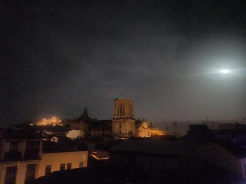 a view of a city at night with a moon at Pensión Duquesa Bed & Breakfast in Granada