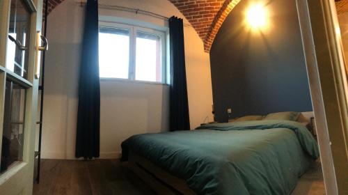 um quarto com uma cama e uma janela em La gaîté de louvignies em Louvignies-Quesnoy