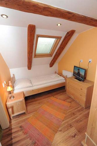 a small bedroom with a bed and a television in it at Garni Hotel St Anna in Boží Dar