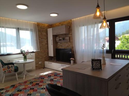 un soggiorno con un divano, un tavolo e una televisione di BELCARA Apartment a Buşteni