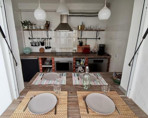una cocina con una mesa con tres platos blancos. en Algarve house, sun, terrace, views and barbecue en Silves