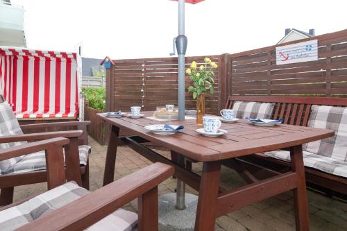 a wooden table with chairs and an umbrella on a patio at Haus Möwe Wohnung Leuchttürmchen in Hörnum