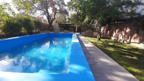 ein blauer Pool in einem Garten mit Bäumen in der Unterkunft La Escondida Salta 5 in Salta