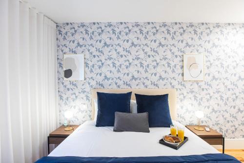 een slaapkamer met een bed met blauwe kussens en behang bij Elegant Downtown 1BR Flat w/ AC by LovelyStay in Porto