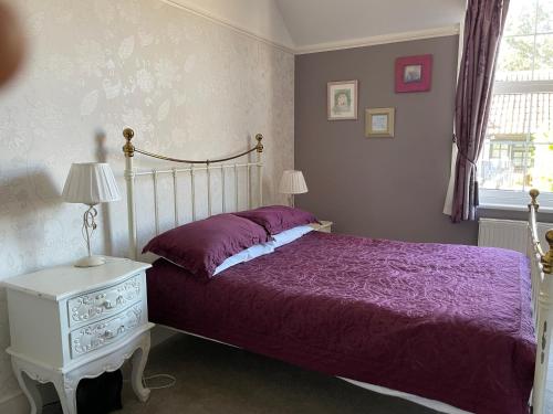 a bedroom with a bed with a purple comforter and a table at The Eagle Tavern in Faringdon