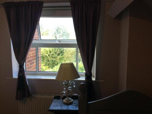 a bedroom with a window with a lamp on a table at The Eagle Tavern in Faringdon