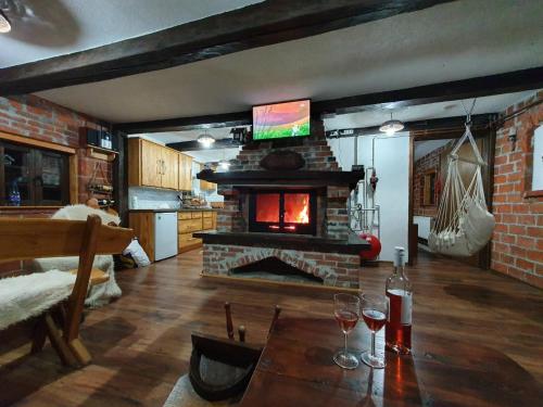 - un salon avec une cheminée et une table avec des verres à vin dans l'établissement Vikendica Bajka, à Despotovac