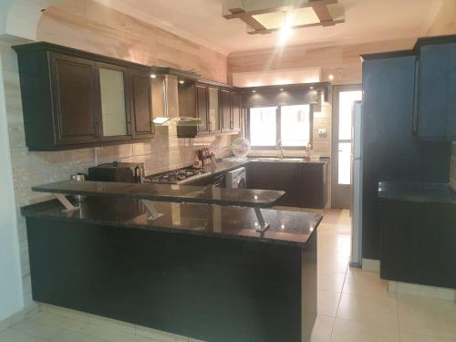 a kitchen with black cabinets and a black counter top at شقة مفروشة فرش فاخر ٣ غرف نوم في طبربور عمان in Amman