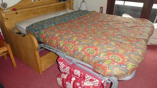 a bed with a colorful comforter and a suitcase at le Vercors en toute simplicite in Autrans