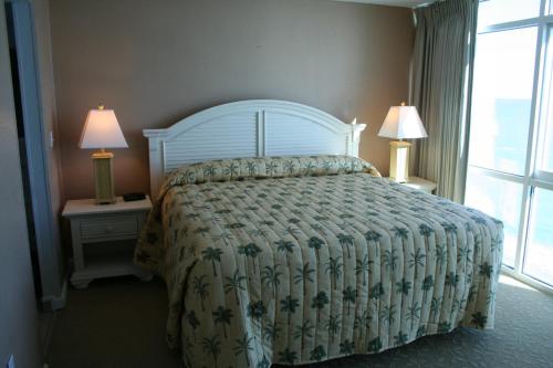 a bedroom with a bed and two night stands with lamps at Club Regency at Regency Towers in Myrtle Beach