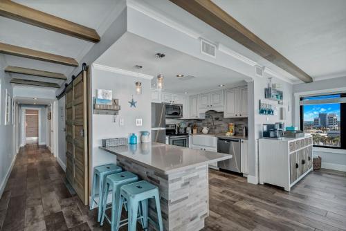 a kitchen with white cabinets and blue stools at Island Winds East Unit 401 in Gulf Shores