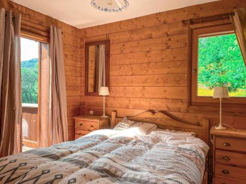 a bedroom with a bed and two windows in it at Bel appartement au calme vue vallée in Sainte-Foy-Tarentaise