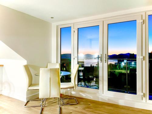 a living room with windows and a table and chairs at The Penthouse in Oban