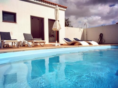 - une piscine avec des chaises et une maison dans l'établissement SURFWHITEHOUSE, à Lajares