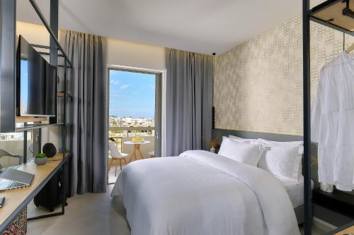 a bedroom with a bed and a desk and a window at Stay 365 Heraklion Apart Hotel in Heraklio Town