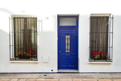 Sitges Rustic Apartments في سيتجيس: باب أزرق على بيت أبيض وبه نافذتين