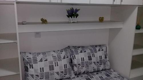 a shelf above a fireplace with a pillow and flowers at Flat Smart 401-Frente a praia-com self-check-in. in Salvador