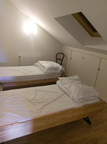 deux lits dans une chambre avec des draps blancs dans l'établissement les hortensias, à Saujon