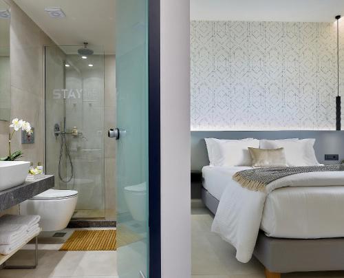 a bedroom with a bed and a bathroom with a shower at Stay 365 Heraklion Apart Hotel in Heraklio Town
