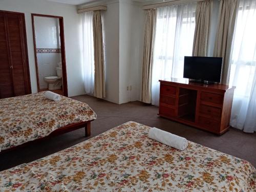 a hotel room with two beds and a flat screen tv at Hotel Real de San Diego in Taxco de Alarcón