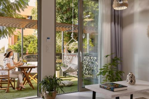 a woman sitting at a table in a room with sliding glass doors at Stay 365 Heraklion Apart Hotel in Heraklio Town