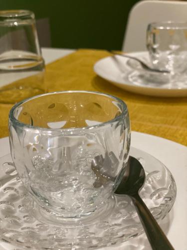 una taza de vidrio sentada en un plato con una cuchara en Via Piave 82 en Cosenza