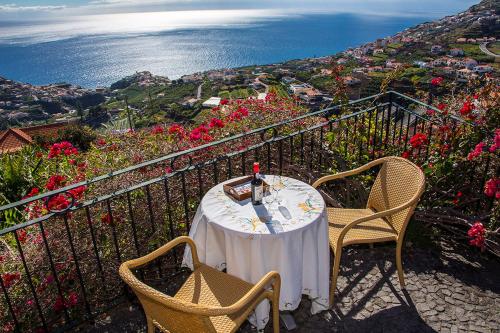 een tafel en stoelen op een balkon met uitzicht op de oceaan bij Vila Afonso in Estreito de Câmara de Lobos